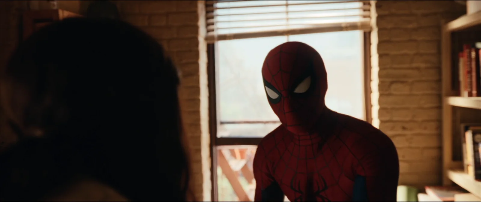 Spider-Man faces another character in a warmly lit room.