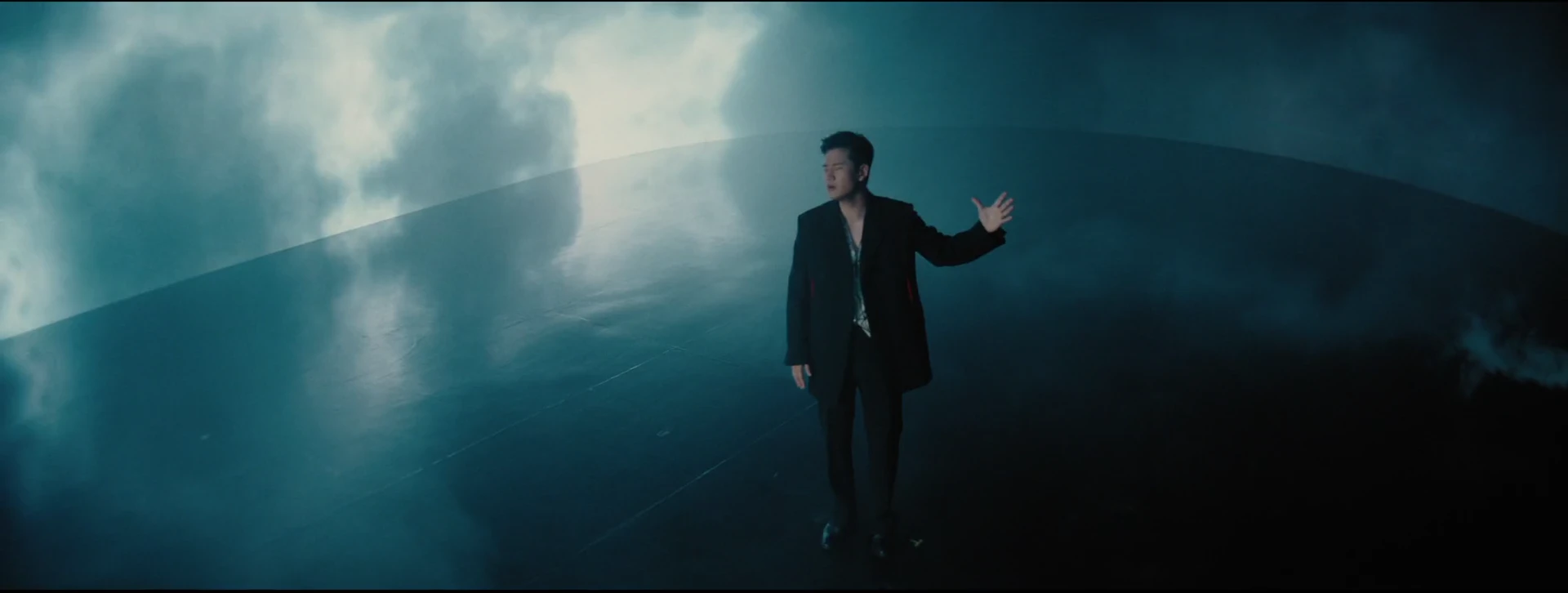 Eric Chou sings inside a blue storm, with shifting clouds and lightning illuminating the surrounding space.