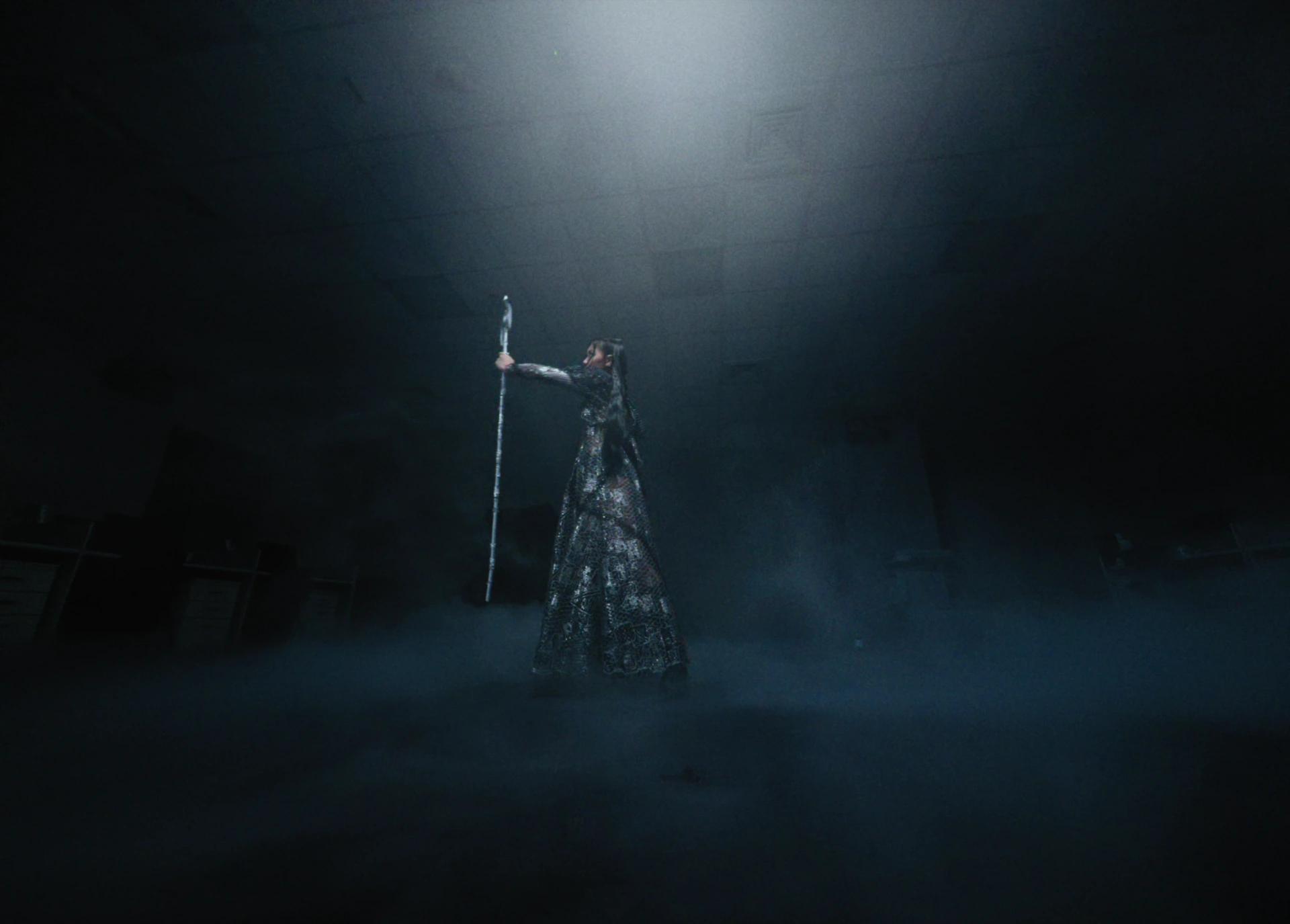 Jasmine Sokko performs alone beneath a shaft of light, surrounded by haze.