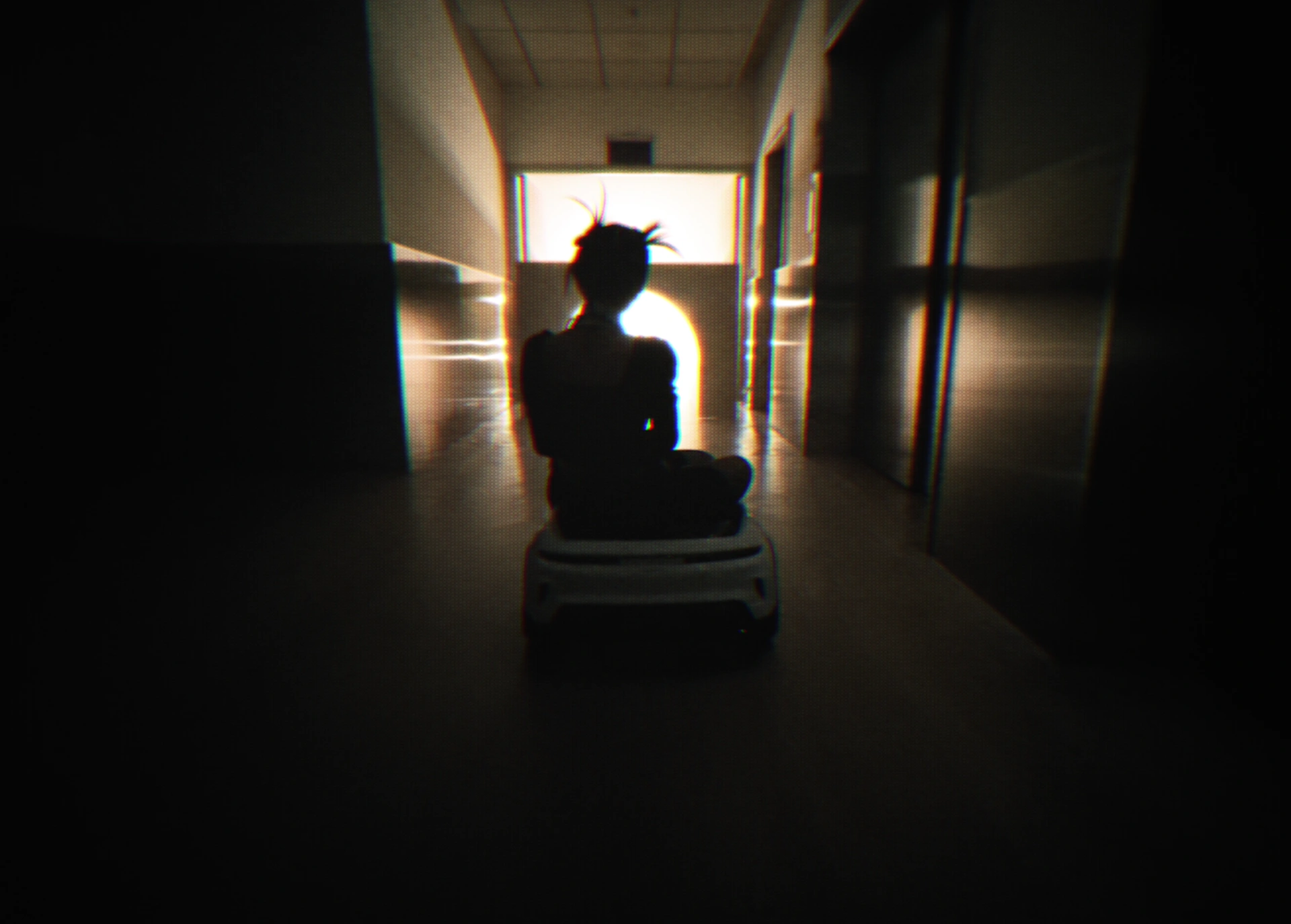 A seated silhouette at the end of a warm backlit corridor.