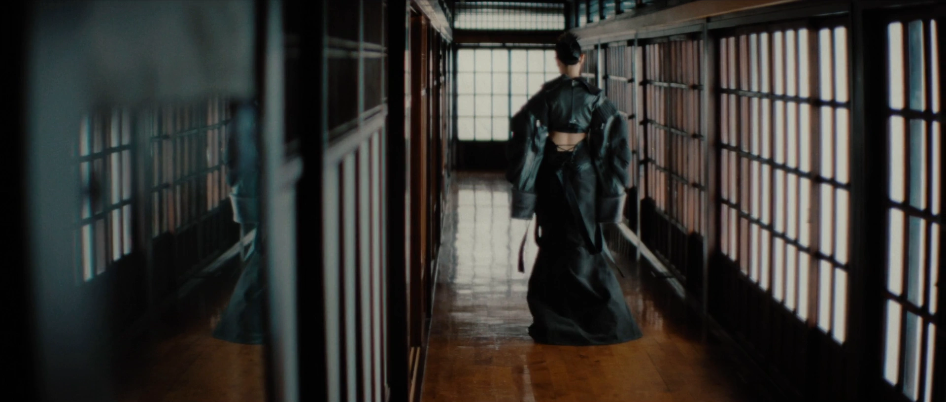 Jasmine Sokko stands in a wooden corridor lined with lattice windows.