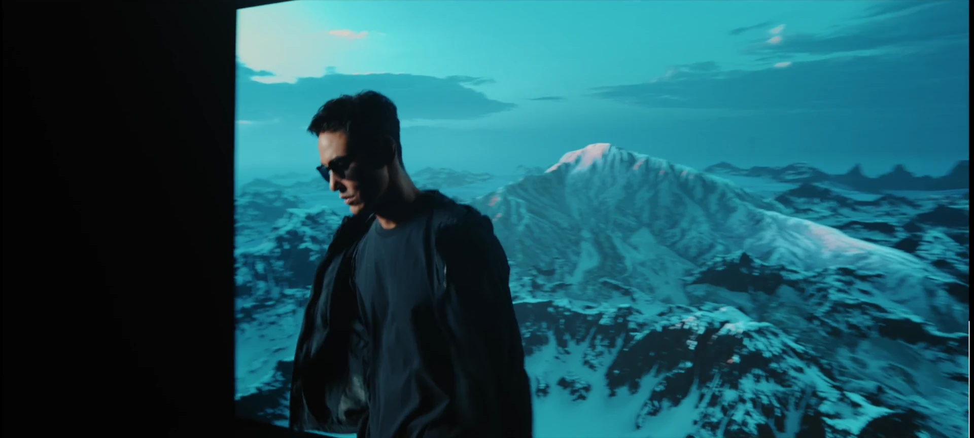 Ethan Juan wearing sunglasses against the alpine landscape.