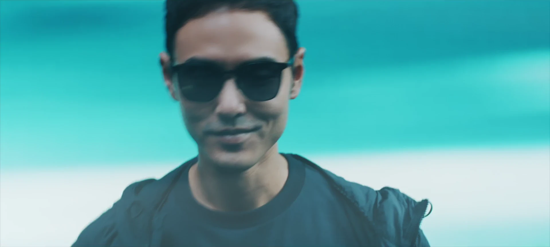 A confident sunglasses portrait in luminous cyan light.