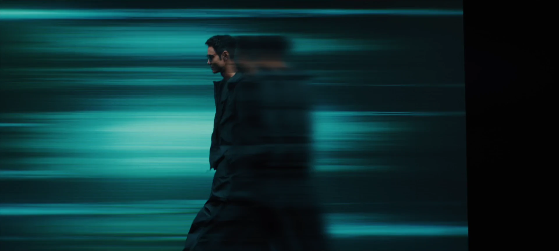 Horizontal cyan trails pass across Ethan Juan and the dark city.