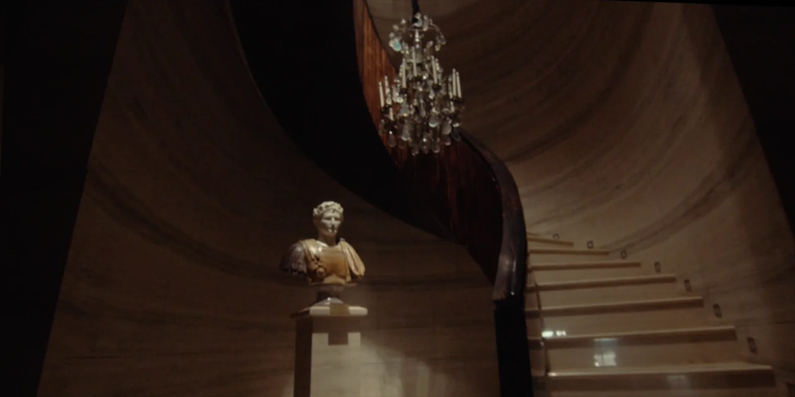 Lian Ju Construction — A sculptural bust beneath a curving staircase