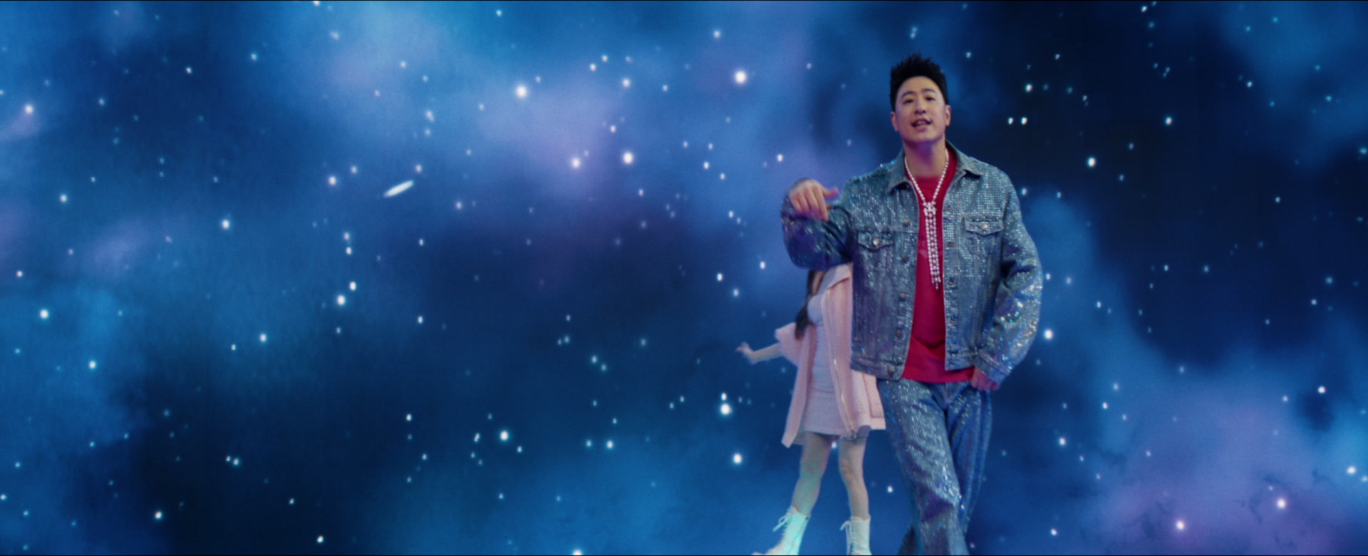 Will Pan performing in a textured blue suit, with Cyndi Wang beyond him against a galaxy backdrop.