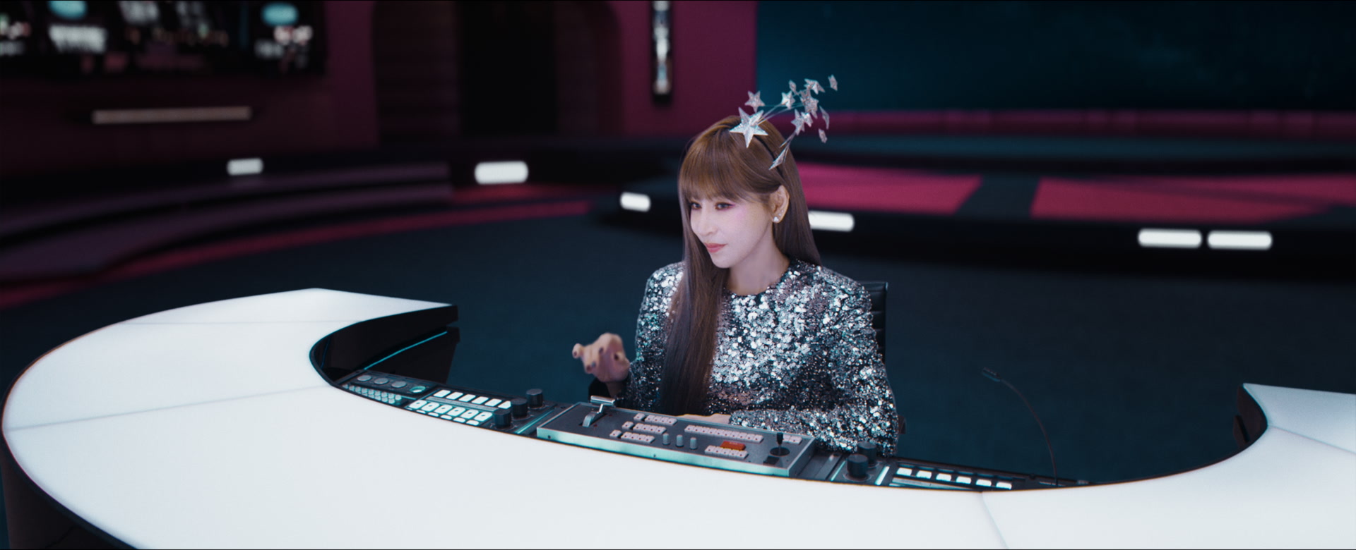 Cyndi Wang operates a curved white command desk in a magenta control room.