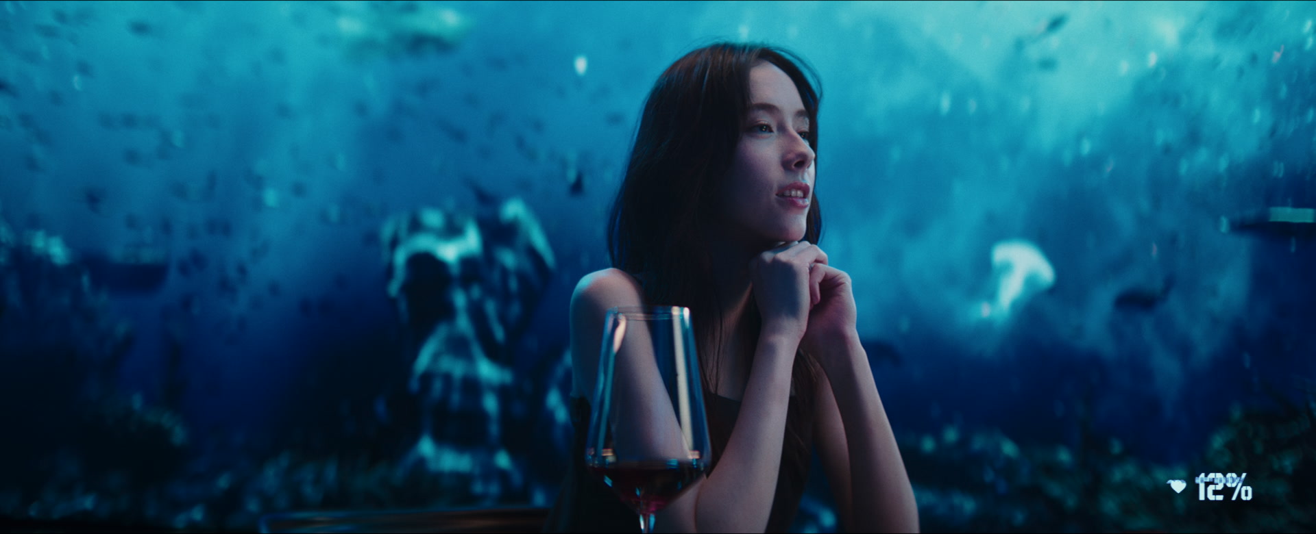 Lead actress Charlize Lamb at a dinner table, framed against an immersive underwater world.