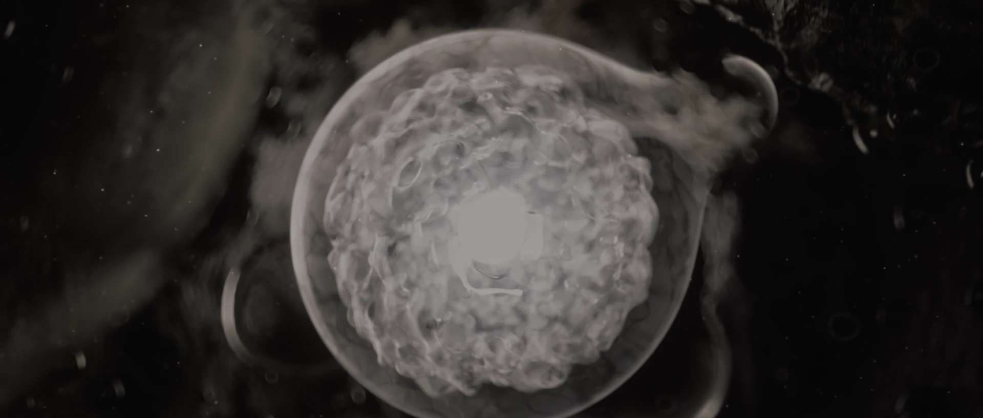 A translucent textured sphere floats among dark stone and particles.