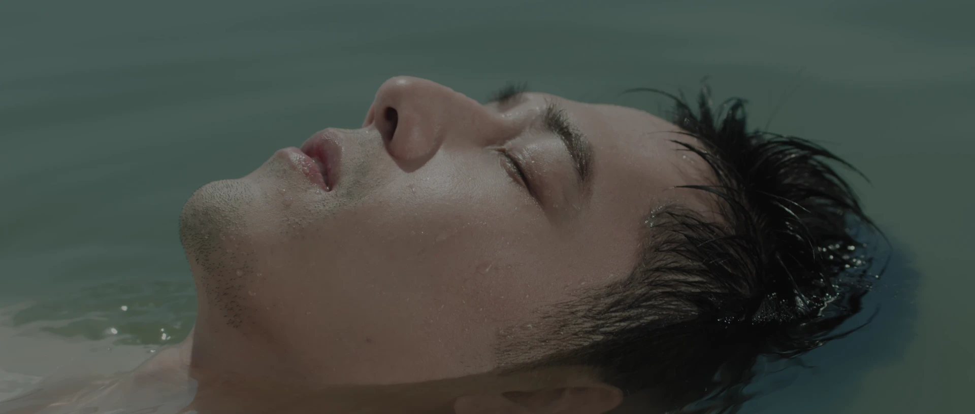 George Hu floats on turquoise water as the viewpoint moves from a close portrait to a wider view.