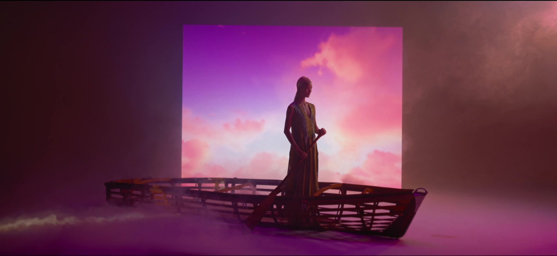Model on a platform before a pink light panel