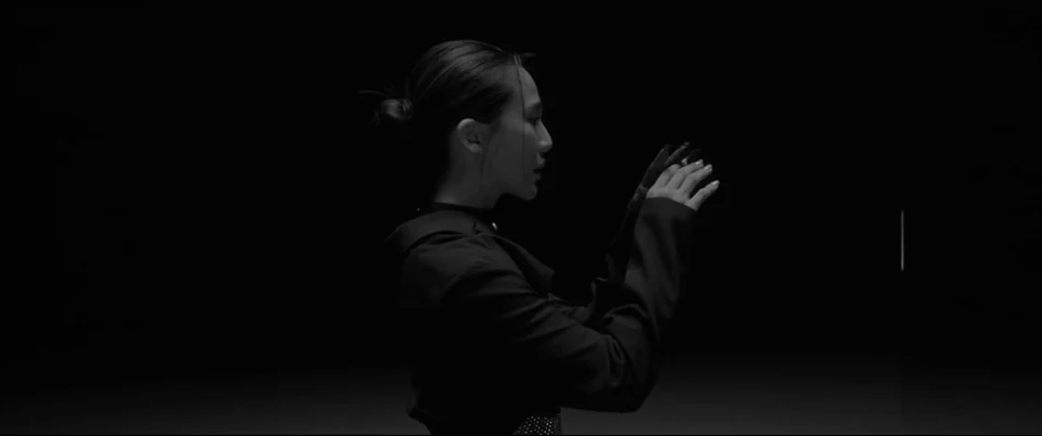 A profile and raised hands against darkness.