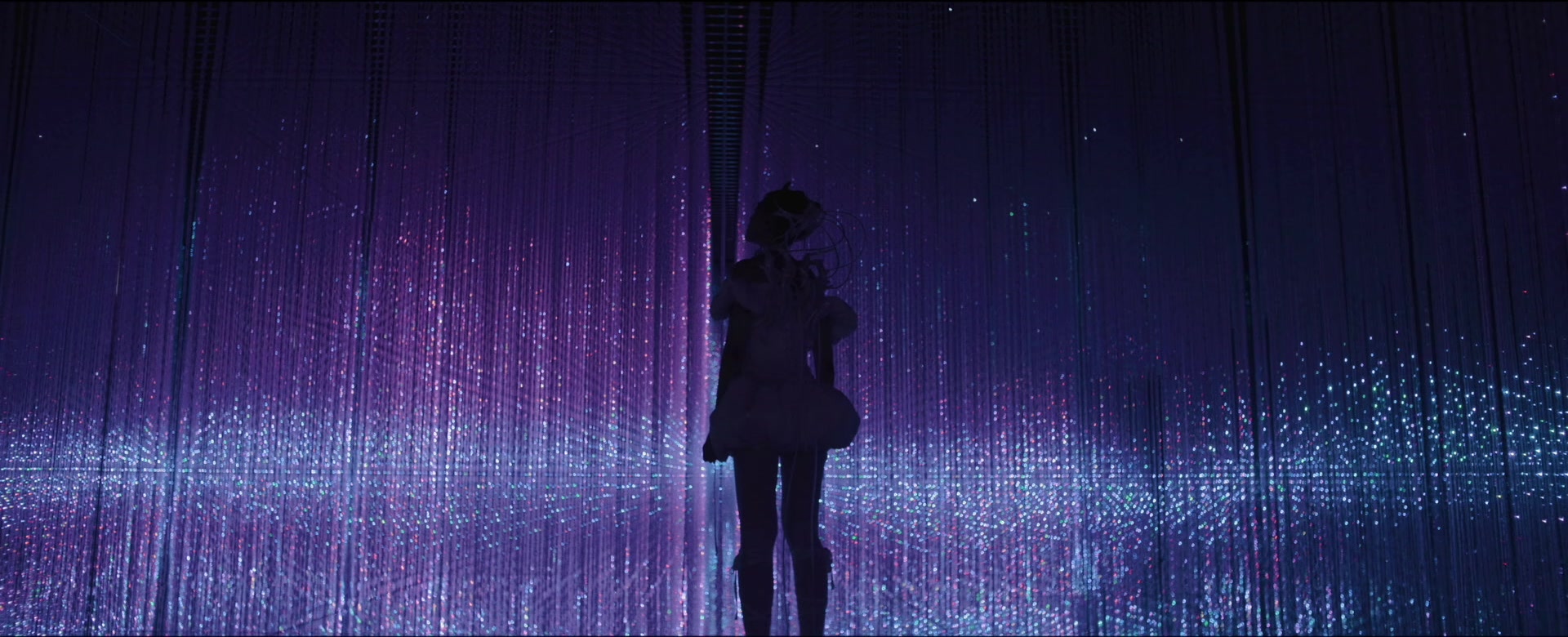 Jasmine Sokko silhouetted against a purple curtain of lights