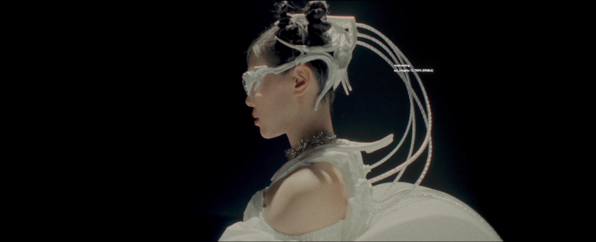 Profile of Jasmine Sokko in a white costume with sculptural head wires